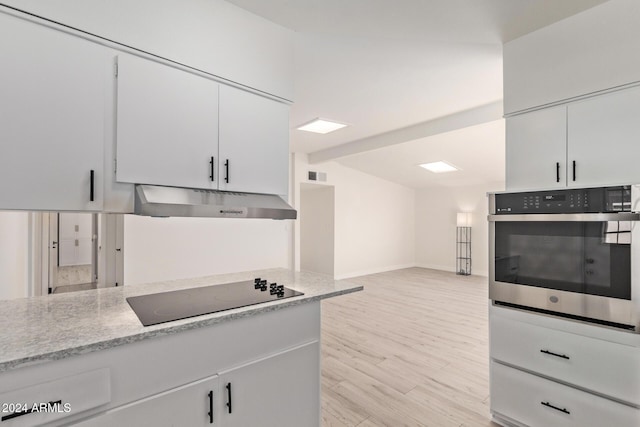 kitchen with light stone counters, light hardwood / wood-style flooring, oven, black electric stovetop, and white cabinets