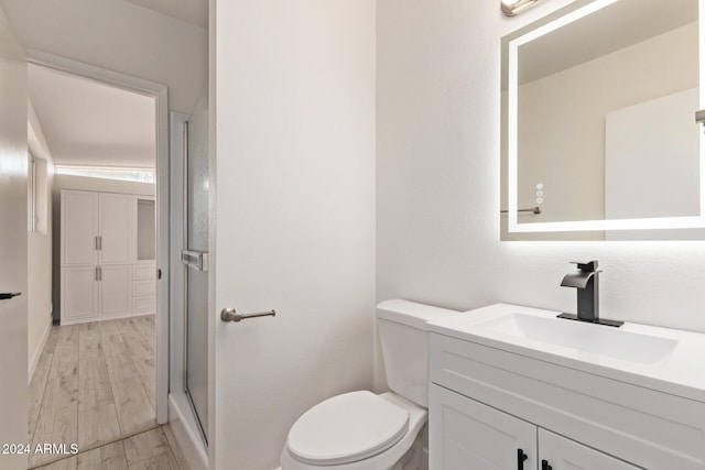 bathroom featuring vanity, wood-type flooring, an enclosed shower, and toilet