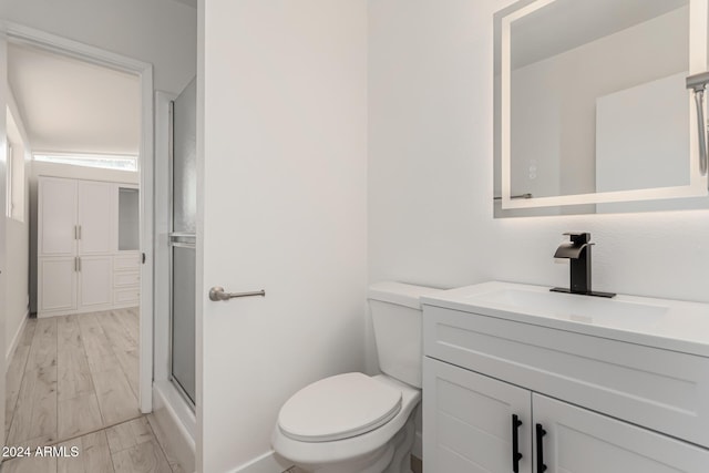 bathroom featuring hardwood / wood-style floors, vanity, toilet, and a shower with shower door