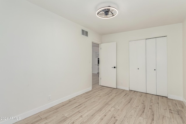 unfurnished bedroom with light wood-type flooring and a closet