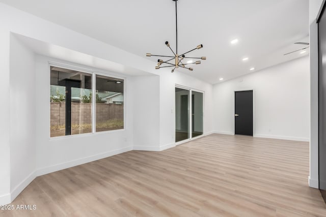 spare room featuring light wood finished floors, baseboards, a chandelier, lofted ceiling, and recessed lighting