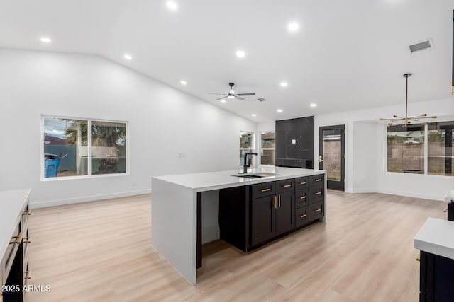 kitchen with visible vents, light countertops, lofted ceiling, dark cabinetry, and a sink