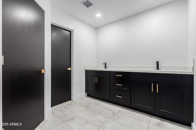 bathroom featuring a sink, visible vents, baseboards, and recessed lighting