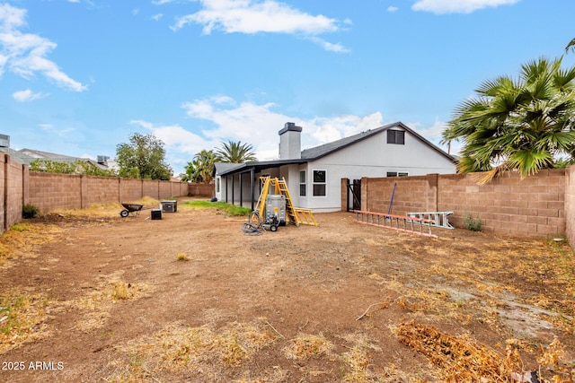 back of house with a fenced backyard and a chimney