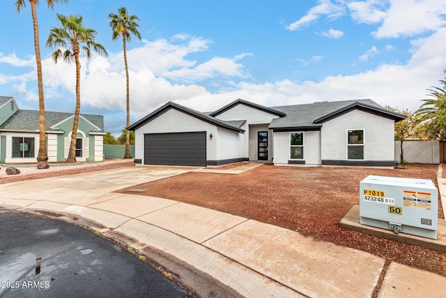 view of front of house featuring stucco siding, concrete driveway, a garage, and fence