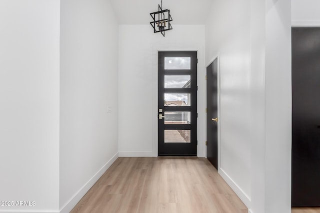 foyer entrance with an inviting chandelier, light wood-type flooring, and baseboards