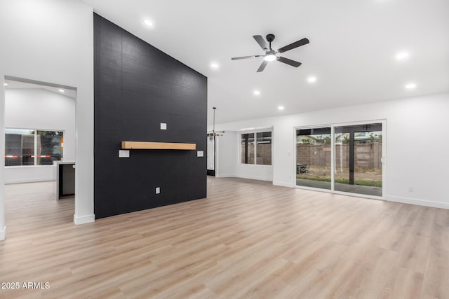 unfurnished living room with light wood finished floors, recessed lighting, a high ceiling, and a ceiling fan