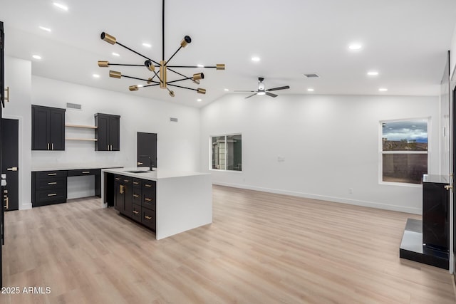 kitchen with dark cabinets, open shelves, a sink, light countertops, and open floor plan