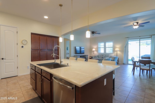 kitchen with decorative light fixtures, sink, stainless steel dishwasher, ceiling fan, and a center island with sink