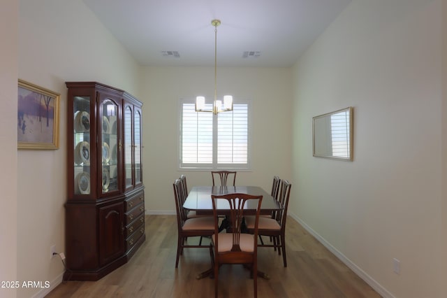 dining area featuring wood-type flooring and a chandelier