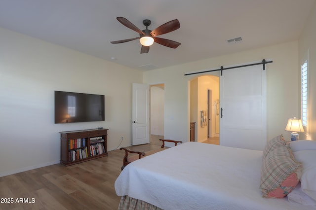 bedroom with hardwood / wood-style flooring, a barn door, and ceiling fan