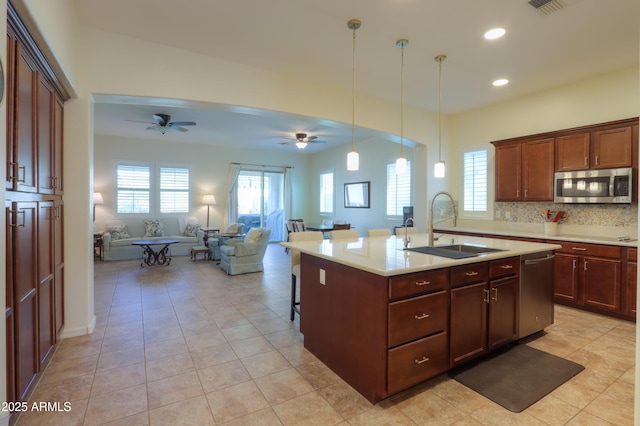 kitchen featuring appliances with stainless steel finishes, sink, a kitchen bar, hanging light fixtures, and a kitchen island with sink