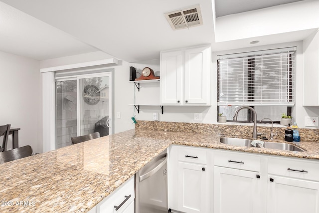 kitchen with light stone counters, sink, stainless steel dishwasher, and white cabinets