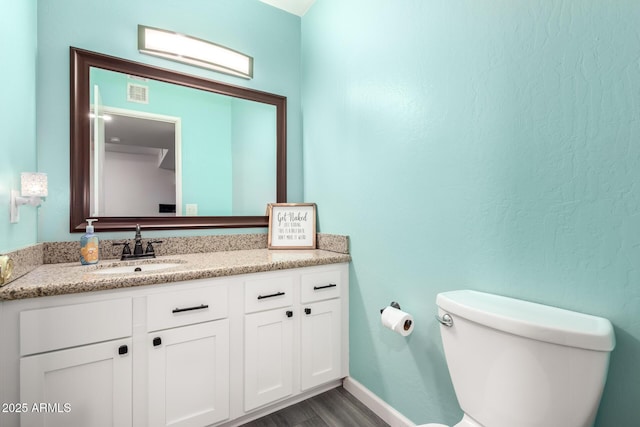 bathroom with hardwood / wood-style flooring, vanity, and toilet