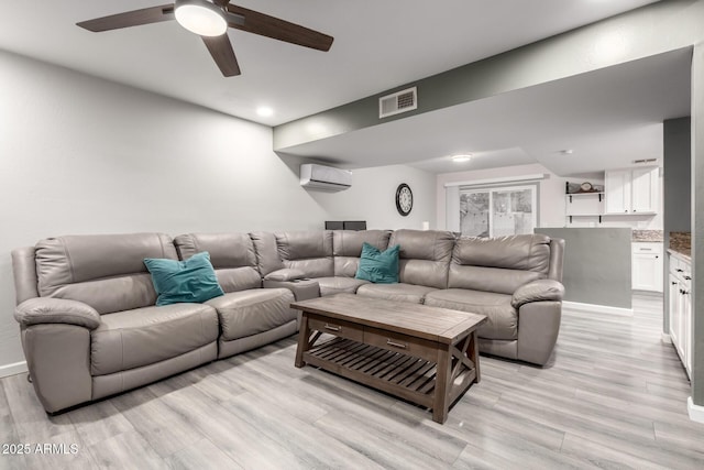 living room featuring ceiling fan, light hardwood / wood-style floors, and a wall unit AC