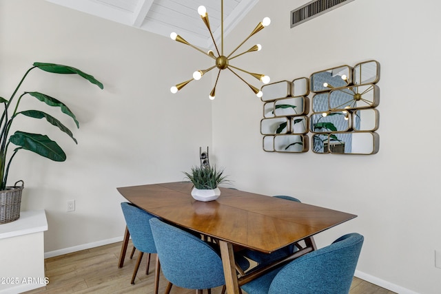 dining area featuring hardwood / wood-style flooring, a notable chandelier, and beamed ceiling