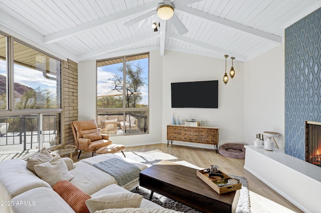 living room with a large fireplace, vaulted ceiling with beams, ceiling fan, wooden ceiling, and light wood-type flooring