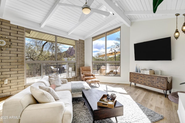 living room with brick wall, vaulted ceiling with beams, ceiling fan, and light hardwood / wood-style flooring