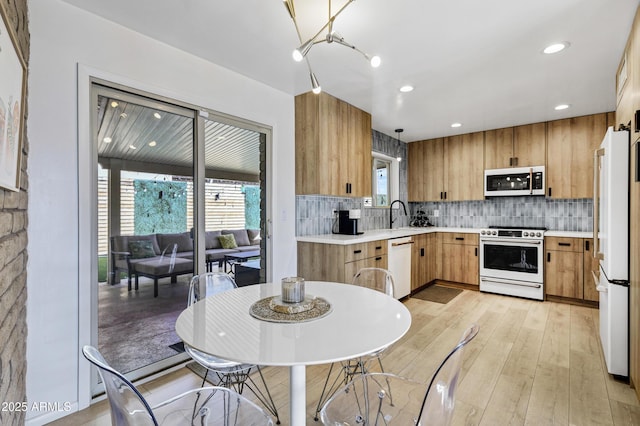 kitchen featuring white appliances, sink, light hardwood / wood-style floors, and backsplash