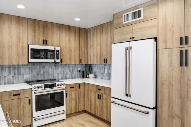 kitchen with white appliances, light hardwood / wood-style floors, and decorative backsplash