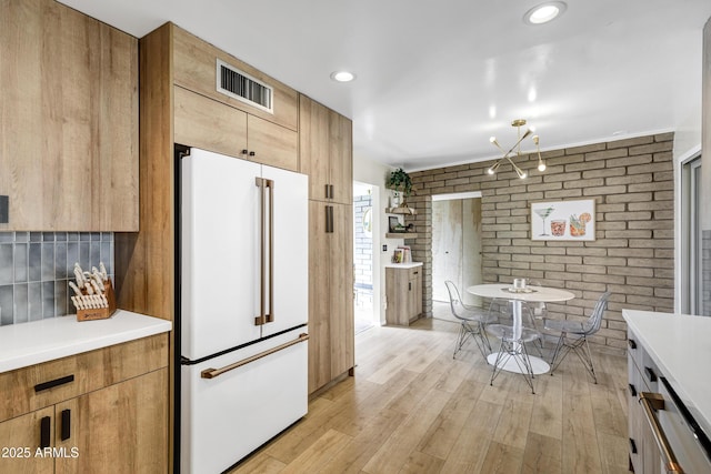 kitchen featuring light hardwood / wood-style flooring, high end white refrigerator, and brick wall