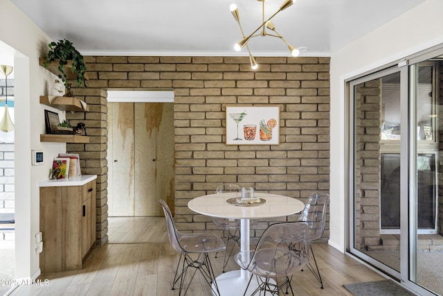 dining space with brick wall and light hardwood / wood-style flooring