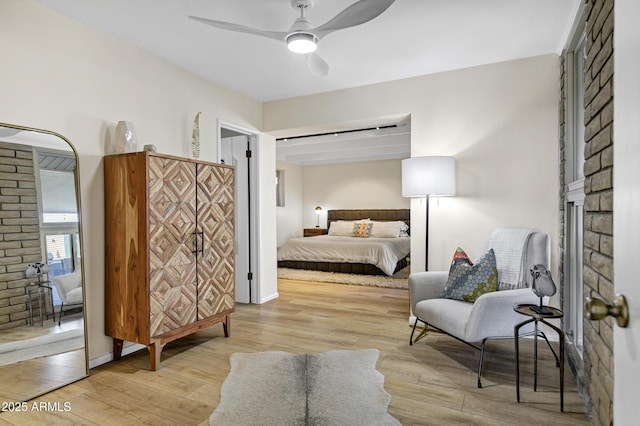 bedroom with a barn door, ceiling fan, and light hardwood / wood-style flooring