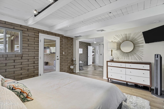 bedroom featuring multiple windows, brick wall, light wood-type flooring, and beam ceiling