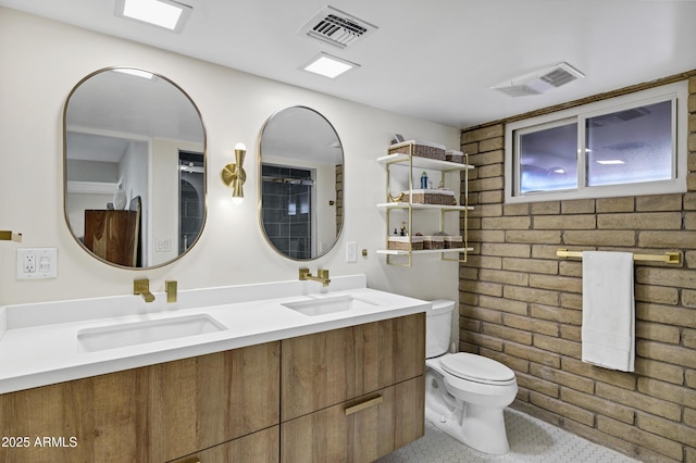 bathroom featuring vanity, tile patterned floors, toilet, and brick wall