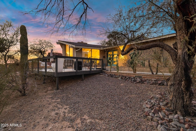 back house at dusk with a wooden deck