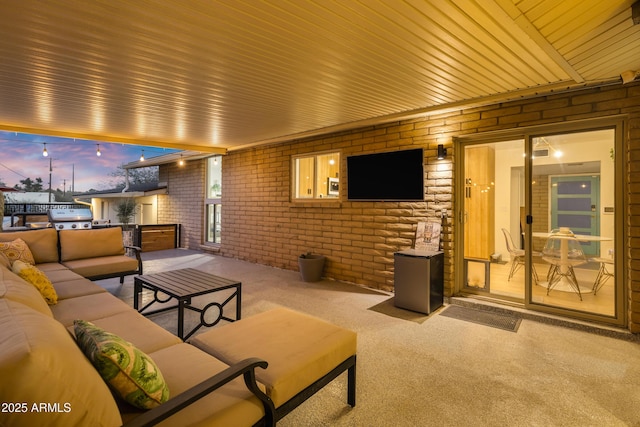 carpeted living room featuring brick wall