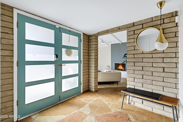 doorway to outside with ceiling fan and a fireplace