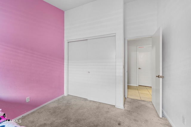 unfurnished bedroom with light carpet and a closet