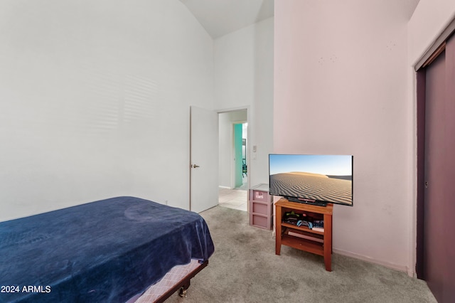 bedroom featuring a closet, high vaulted ceiling, and light colored carpet