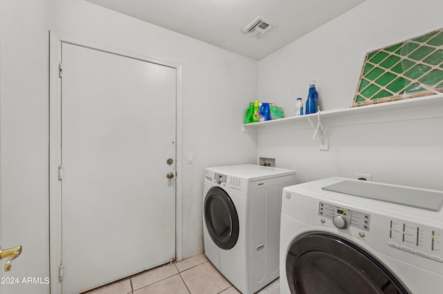 laundry area with washer and dryer and light tile patterned floors