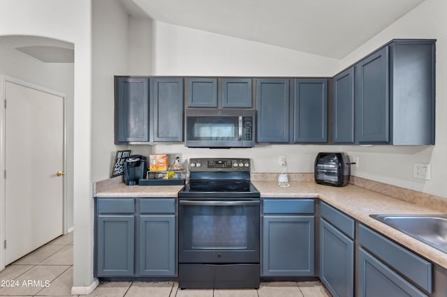 kitchen with light tile patterned floors, stainless steel appliances, lofted ceiling, and blue cabinetry