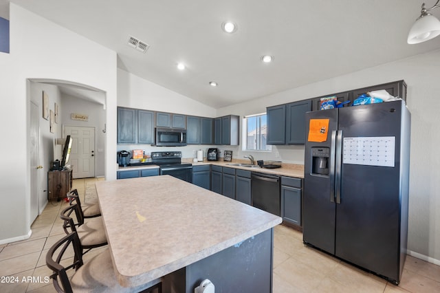 kitchen with a kitchen island, hanging light fixtures, vaulted ceiling, light tile patterned floors, and appliances with stainless steel finishes