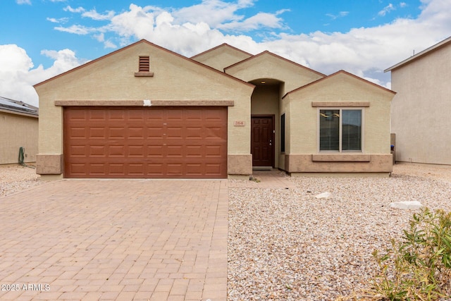 view of front facade with decorative driveway, an attached garage, and stucco siding