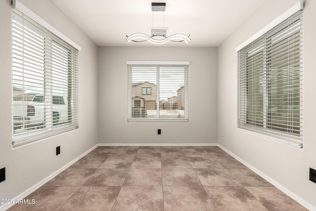 spare room with tile patterned floors, visible vents, an inviting chandelier, and baseboards