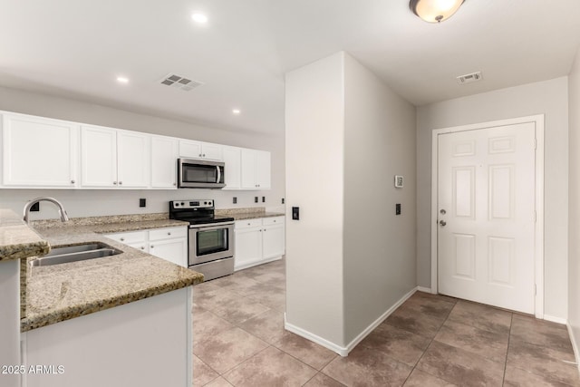 kitchen featuring a sink, light stone counters, visible vents, and stainless steel appliances