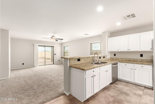 kitchen with visible vents, light colored carpet, a peninsula, white cabinets, and a sink