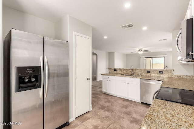 kitchen with a ceiling fan, a sink, light stone counters, white cabinetry, and stainless steel appliances