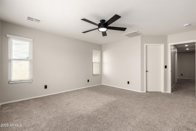 carpeted spare room with visible vents, baseboards, and ceiling fan