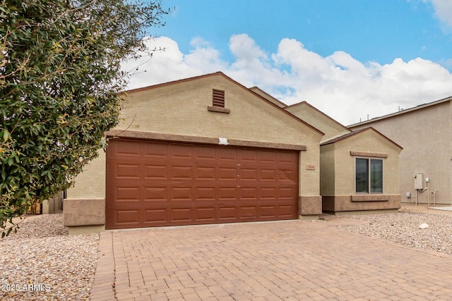 view of front facade with decorative driveway, a garage, and stucco siding