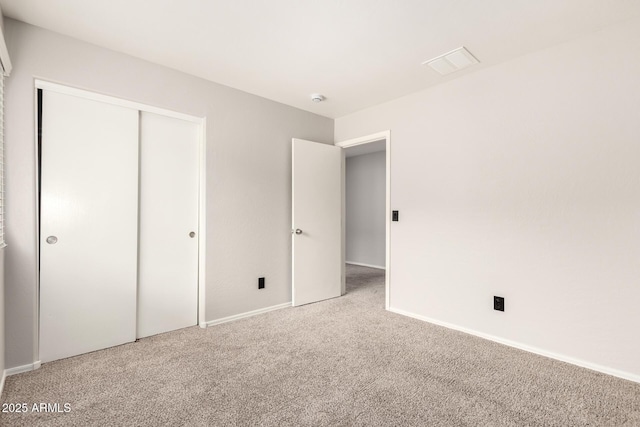 unfurnished bedroom with baseboards, a closet, carpet floors, and visible vents