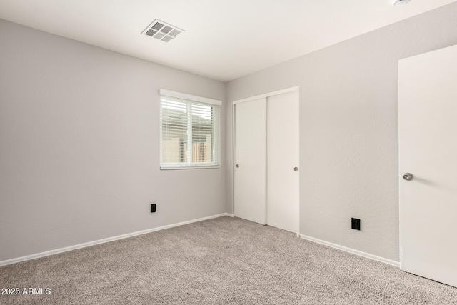 unfurnished bedroom featuring a closet, visible vents, baseboards, and carpet floors