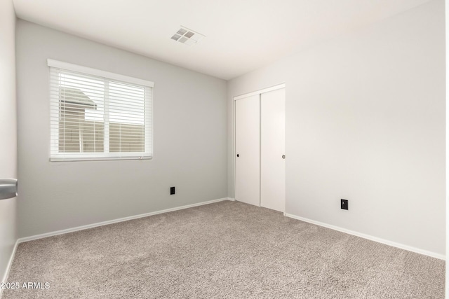 unfurnished bedroom featuring a closet, visible vents, baseboards, and carpet floors