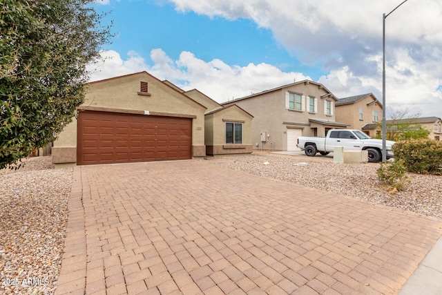 view of front of home featuring decorative driveway, an attached garage, and stucco siding