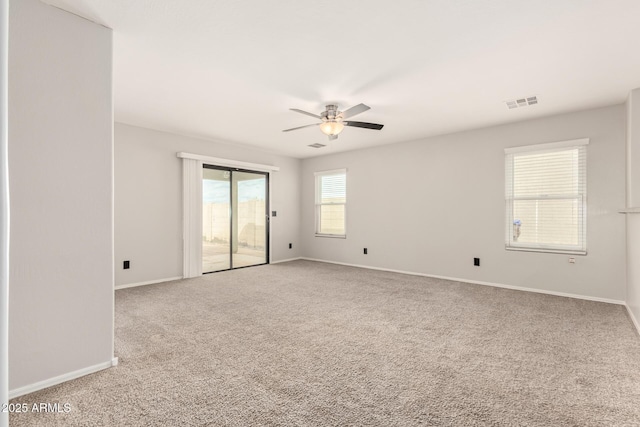 carpeted empty room with visible vents, a ceiling fan, and baseboards