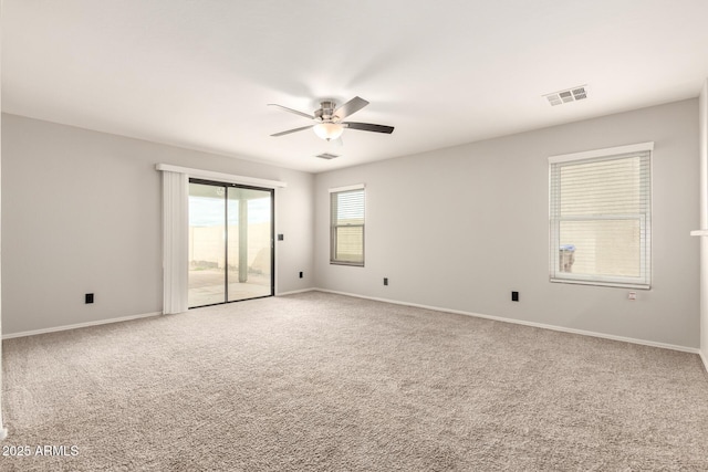 carpeted empty room featuring a ceiling fan, visible vents, and baseboards